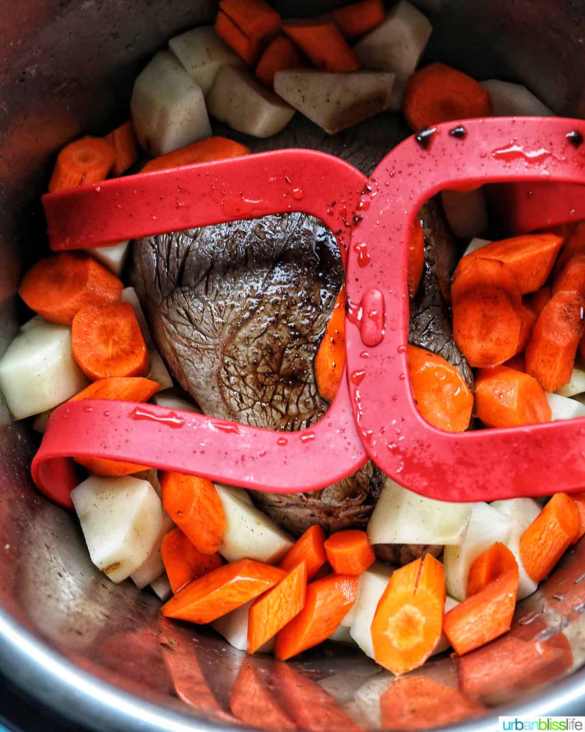 sirloin tip roast, carrots, and potatoes in a red sling in the Instant Pot.