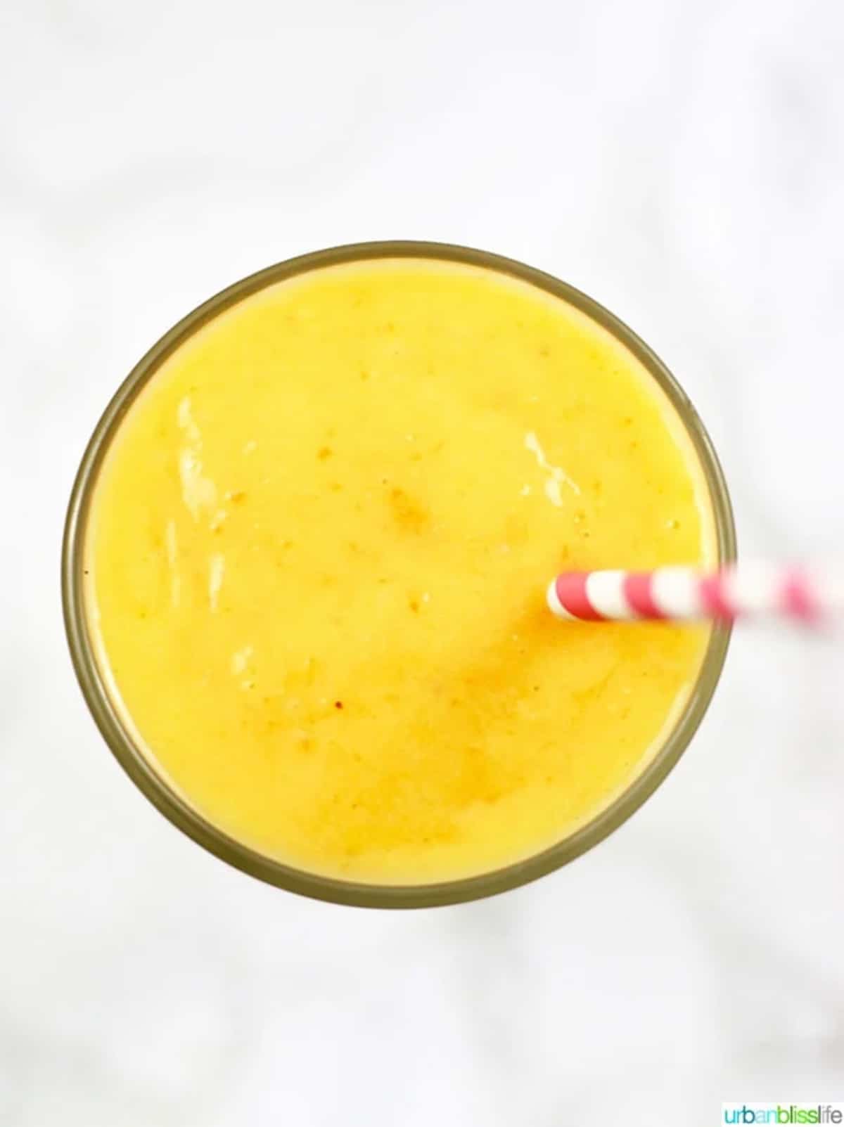 mango carrot smoothie overhead in glass with straw