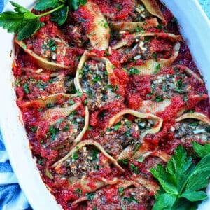 A casserole dish full of stuffed shells with ground beef.