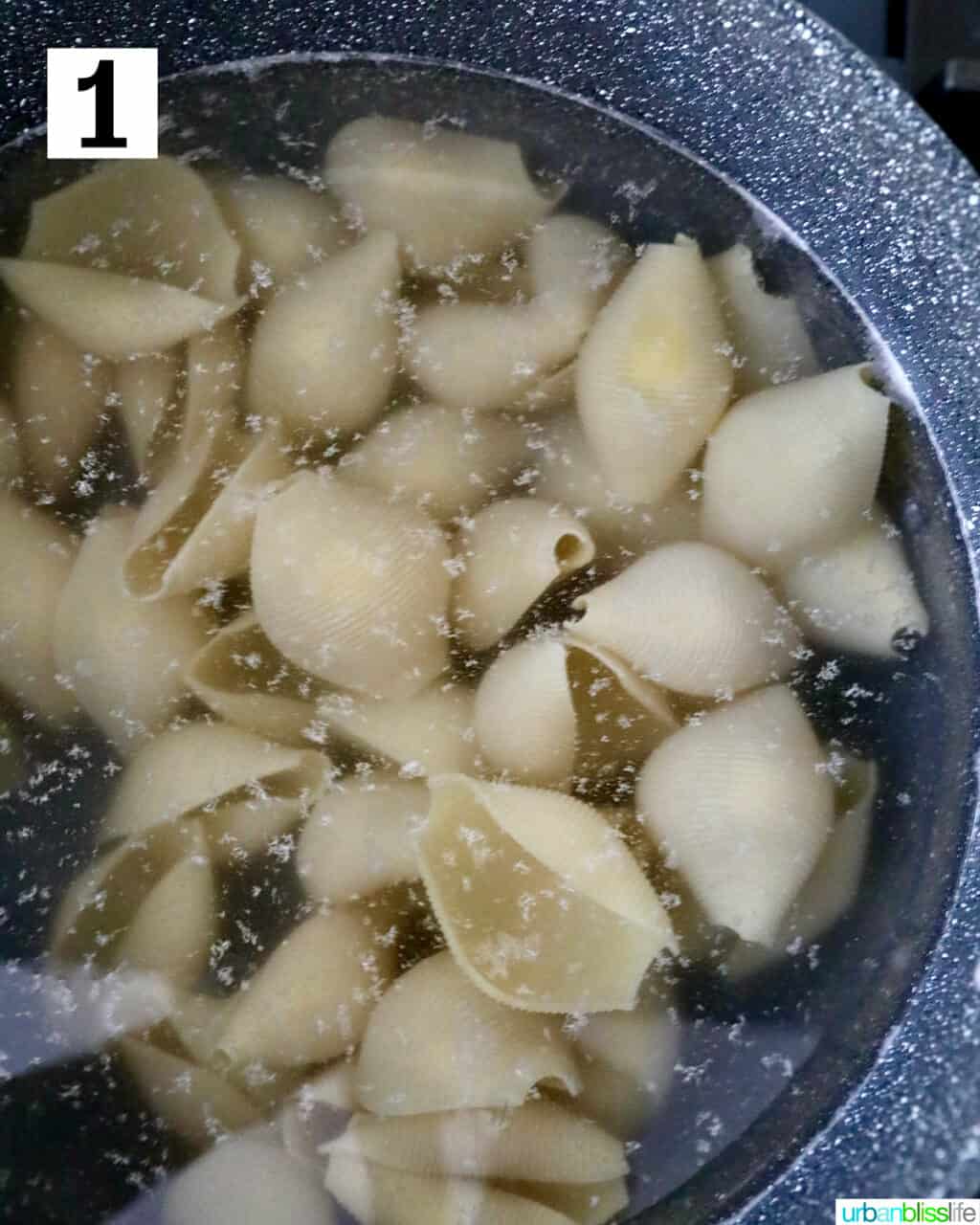 jumbo pasta shells cooking in a pot of boiling water.