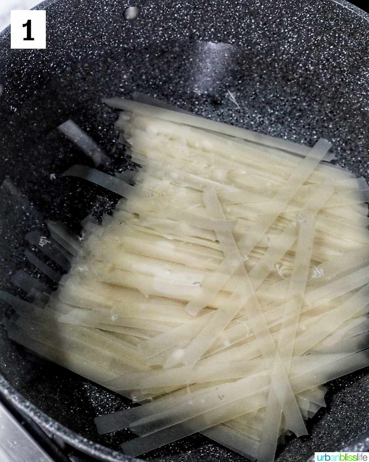 large pot with boiling water cooking wide rice noodles.