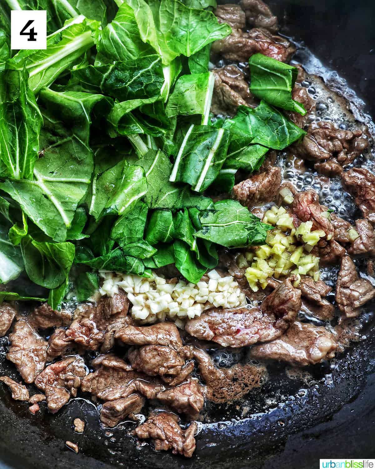 beef and bok choy cooking in a wok.