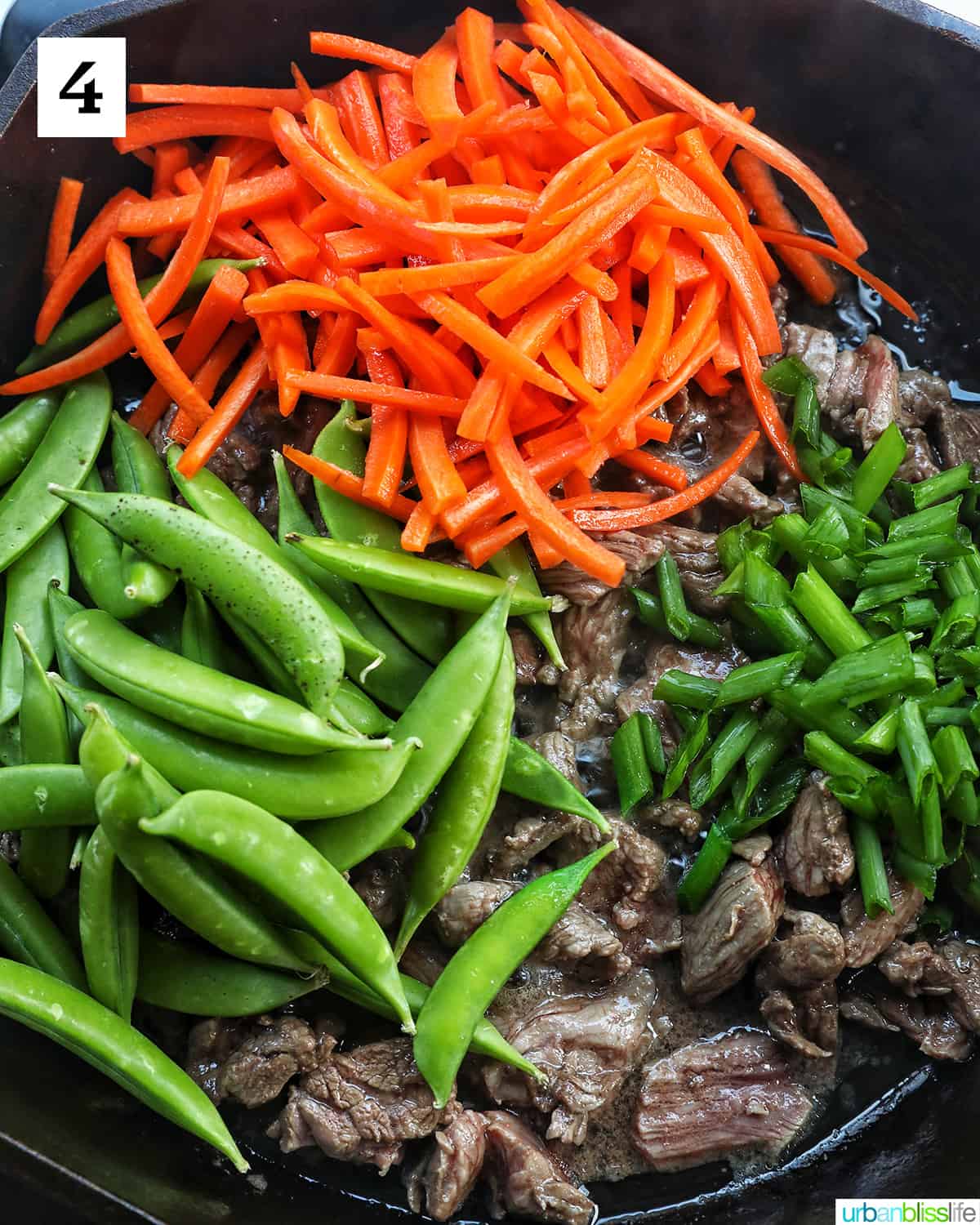 snap peas, carrots, scallions, and steak in a cast iron skillet.