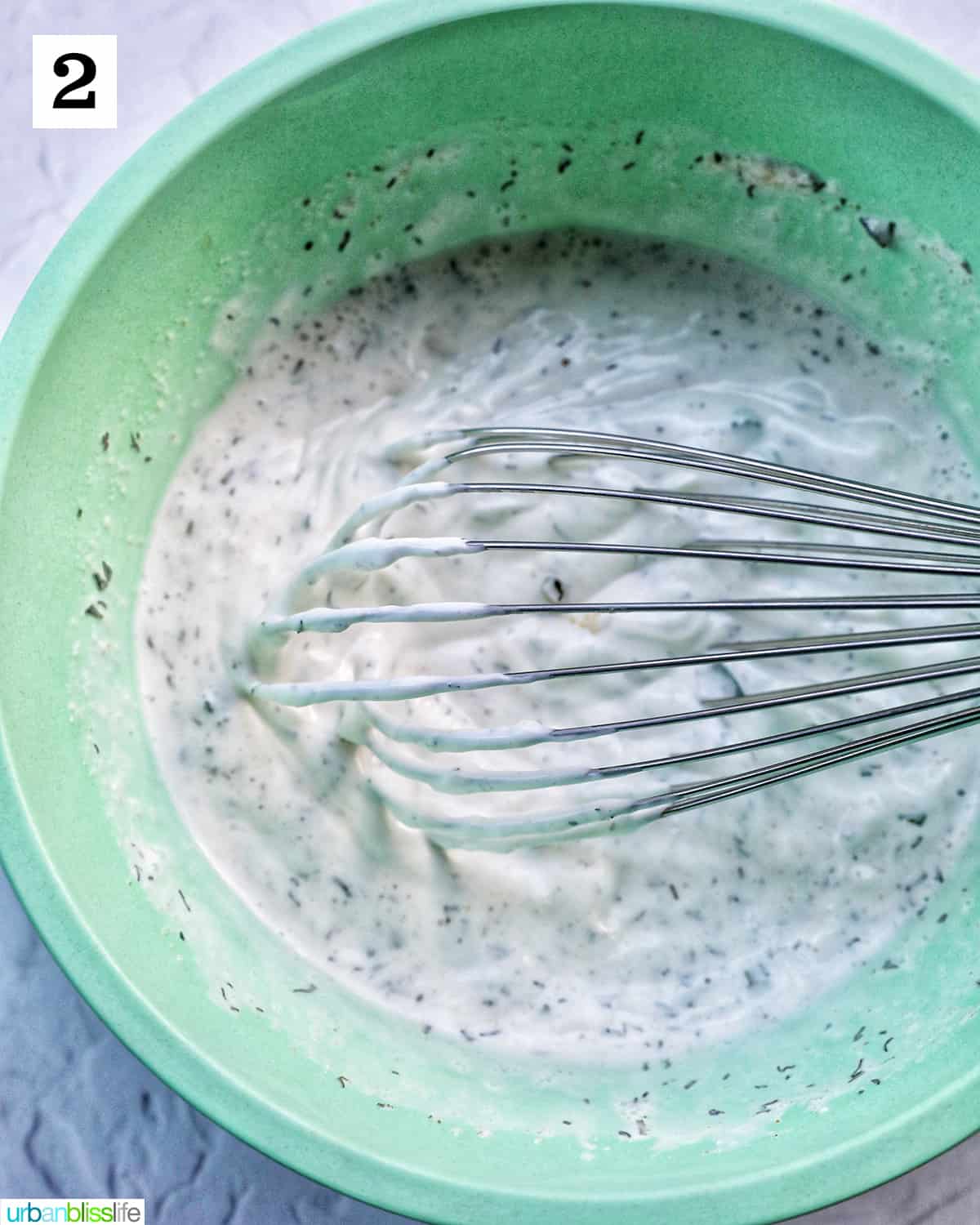 whisk in green bowl of homemade dairy free ranch dressing.