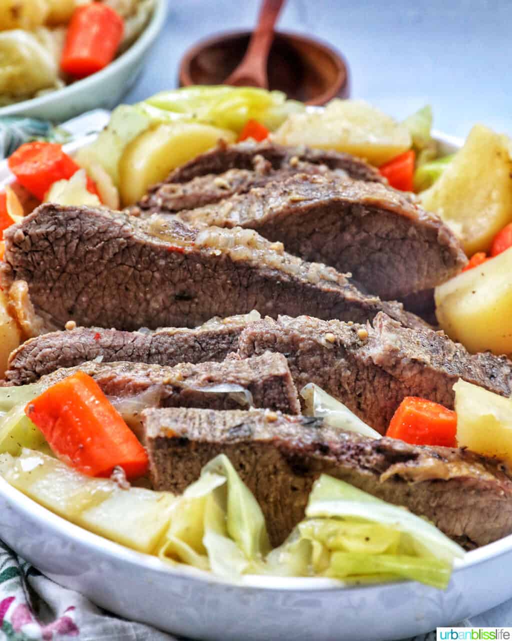 bowl of sliced dutch oven brisket with carrots, potatoes, and cabbage.