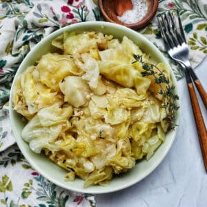 bowl of cooked instant pot cabbage with thyme sprigs and forks.