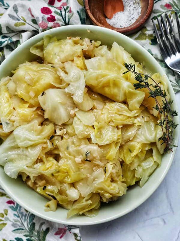 bowl of cooked instant pot cabbage with thyme sprigs and forks.