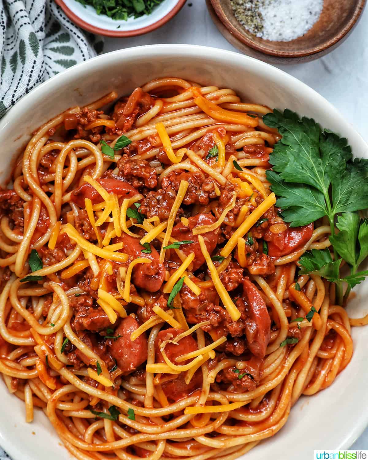 Jolibee spaghetti in a bowl with parsley, shredded cheese, and side of salt and pepper.