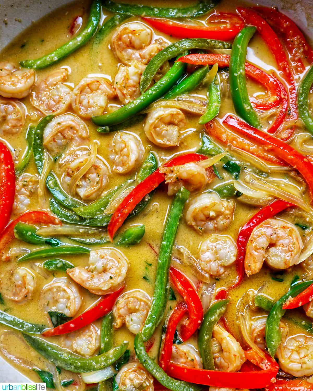 Thai Basil Shrimp with red and green peppers in sauce in a pan.