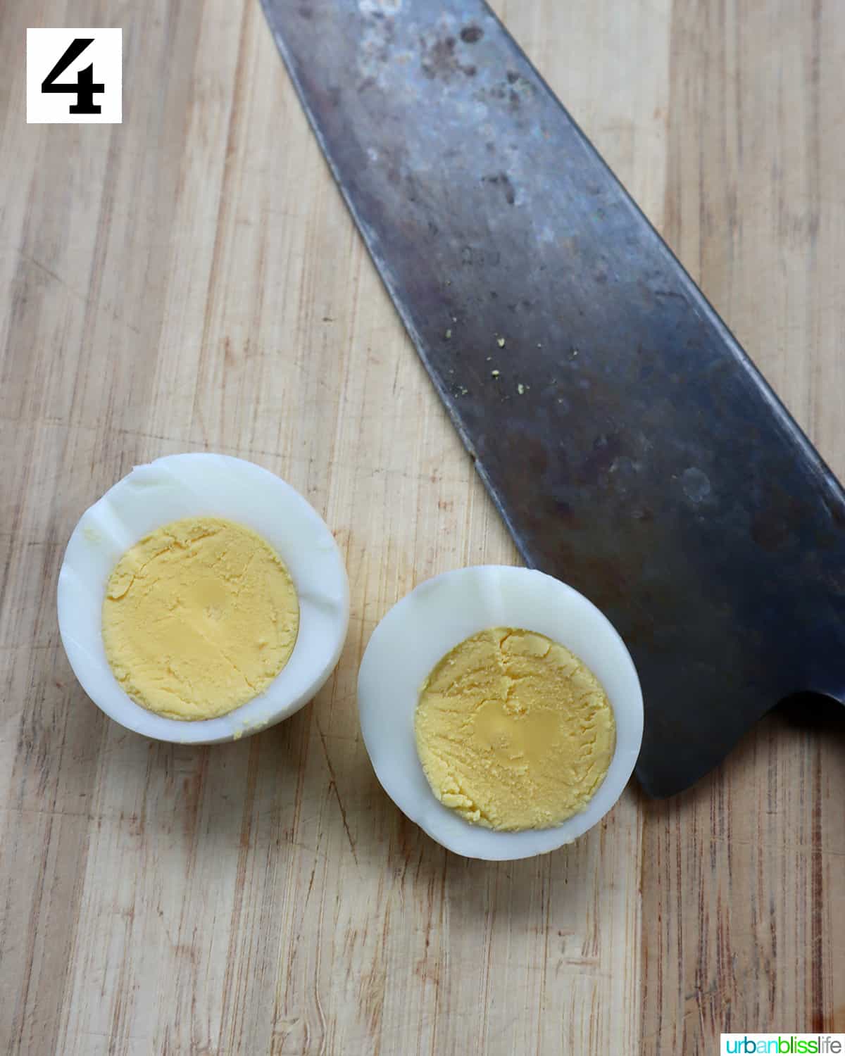 knife with two halves of a hardboiled egg on a cutting board.