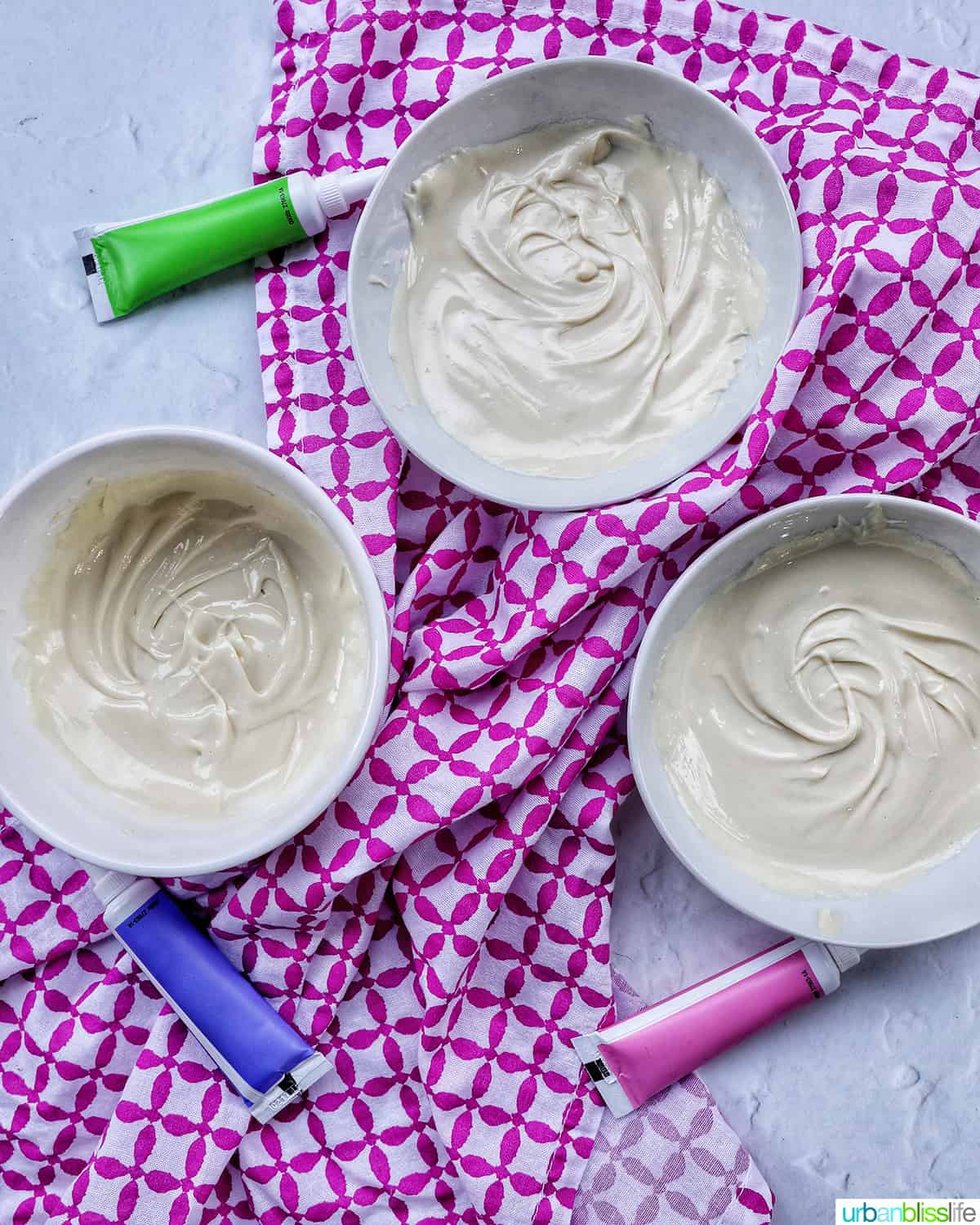 bowls of white chocolate with food coloring tubes next to them.