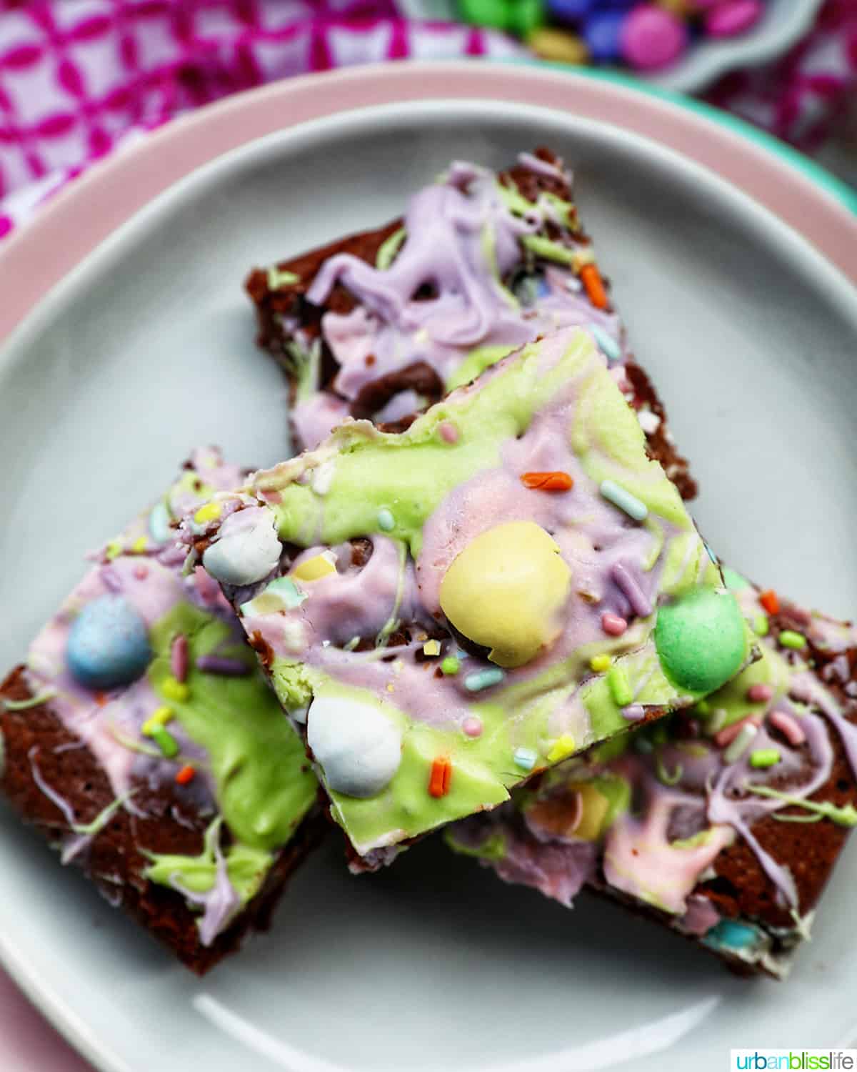 stack of colorful Easter brownies on a white and pink plate.
