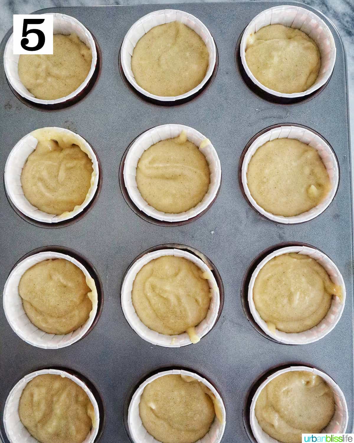 a muffin tin with cupcake liners filled with cupcake batter.