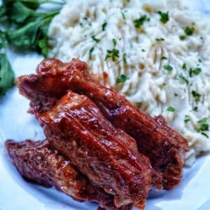 plate of Instant Pot country style ribs and mashed potatoes with herbs.