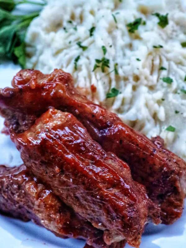 plate of Instant Pot country style ribs and mashed potatoes with herbs.