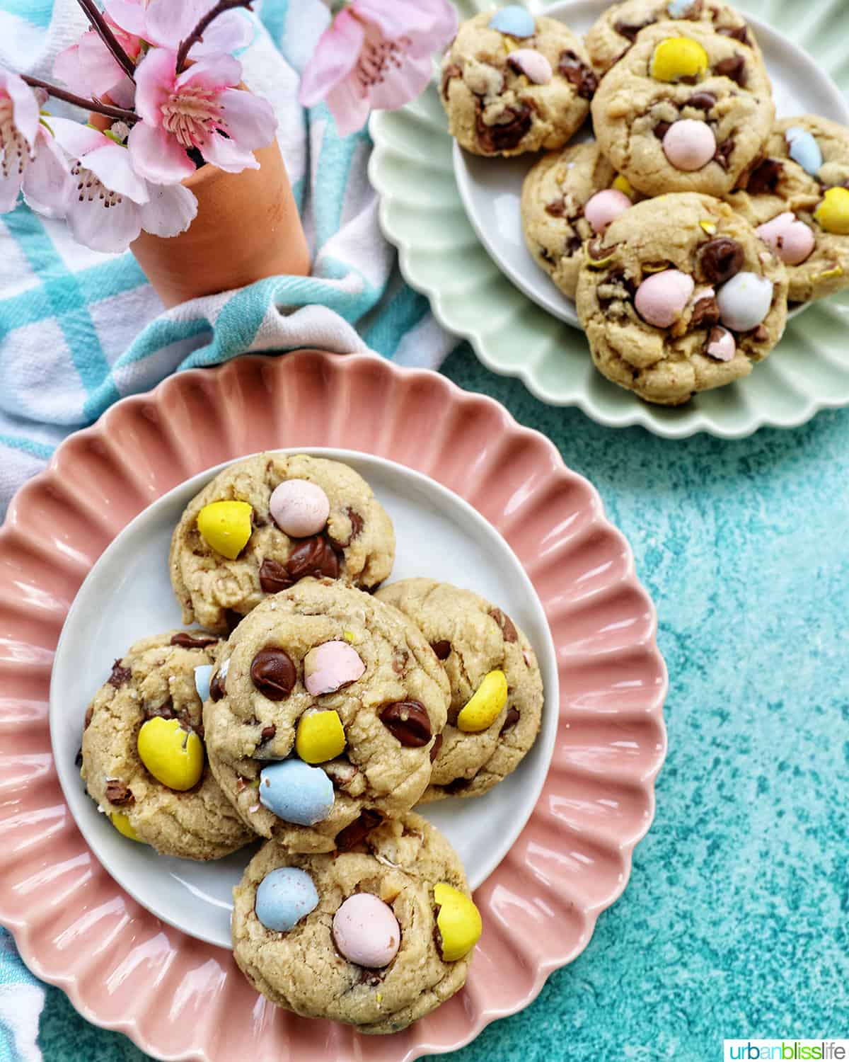 stack of Easter mini egg cookies on a pink scalloped plate and green plate.