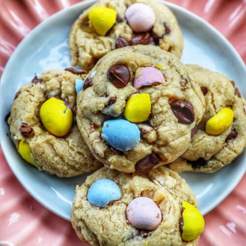 stack of Easter mini egg cookies on a pink scalloped plate.