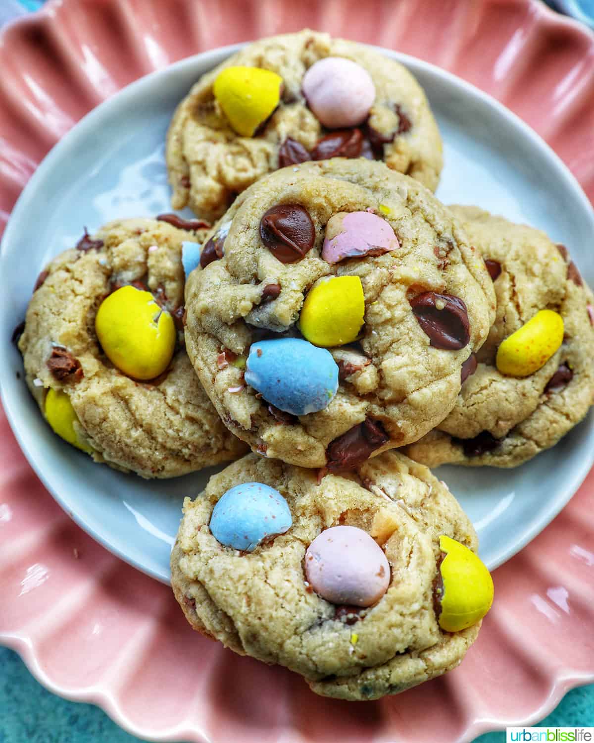 stack of Easter mini egg cookies on a pink scalloped plate.