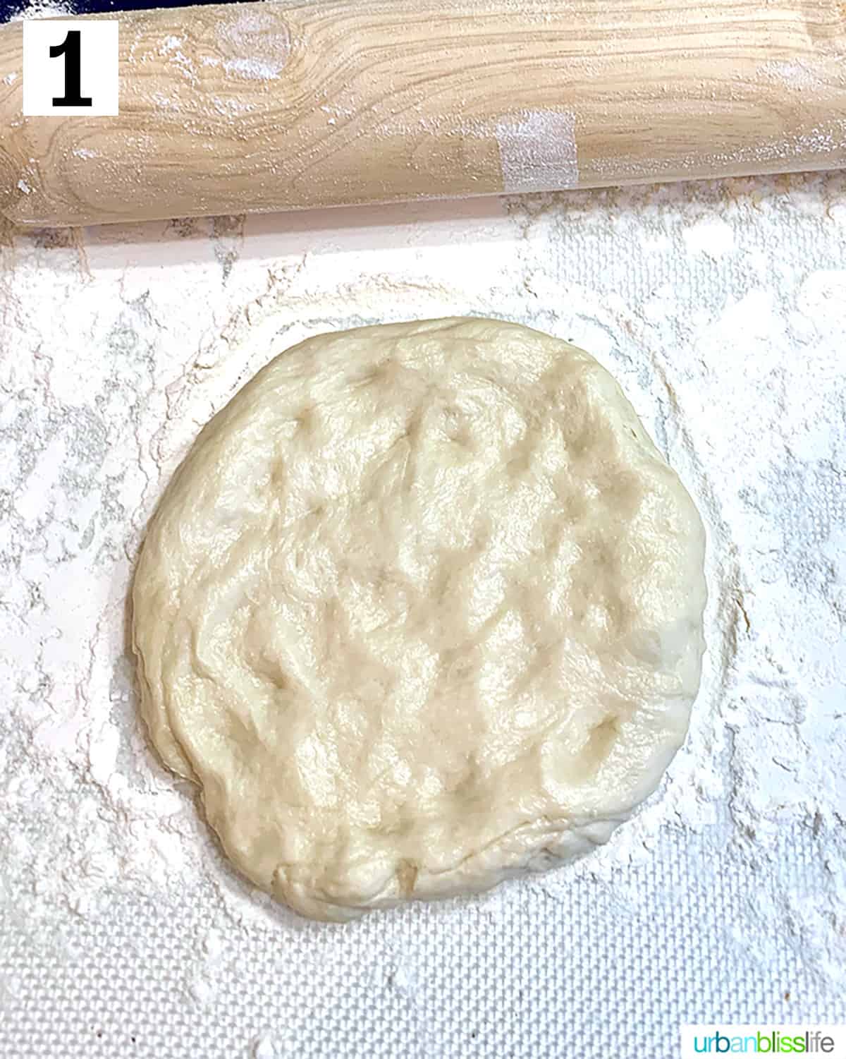 rolling pin with pizza dough on floured surface.