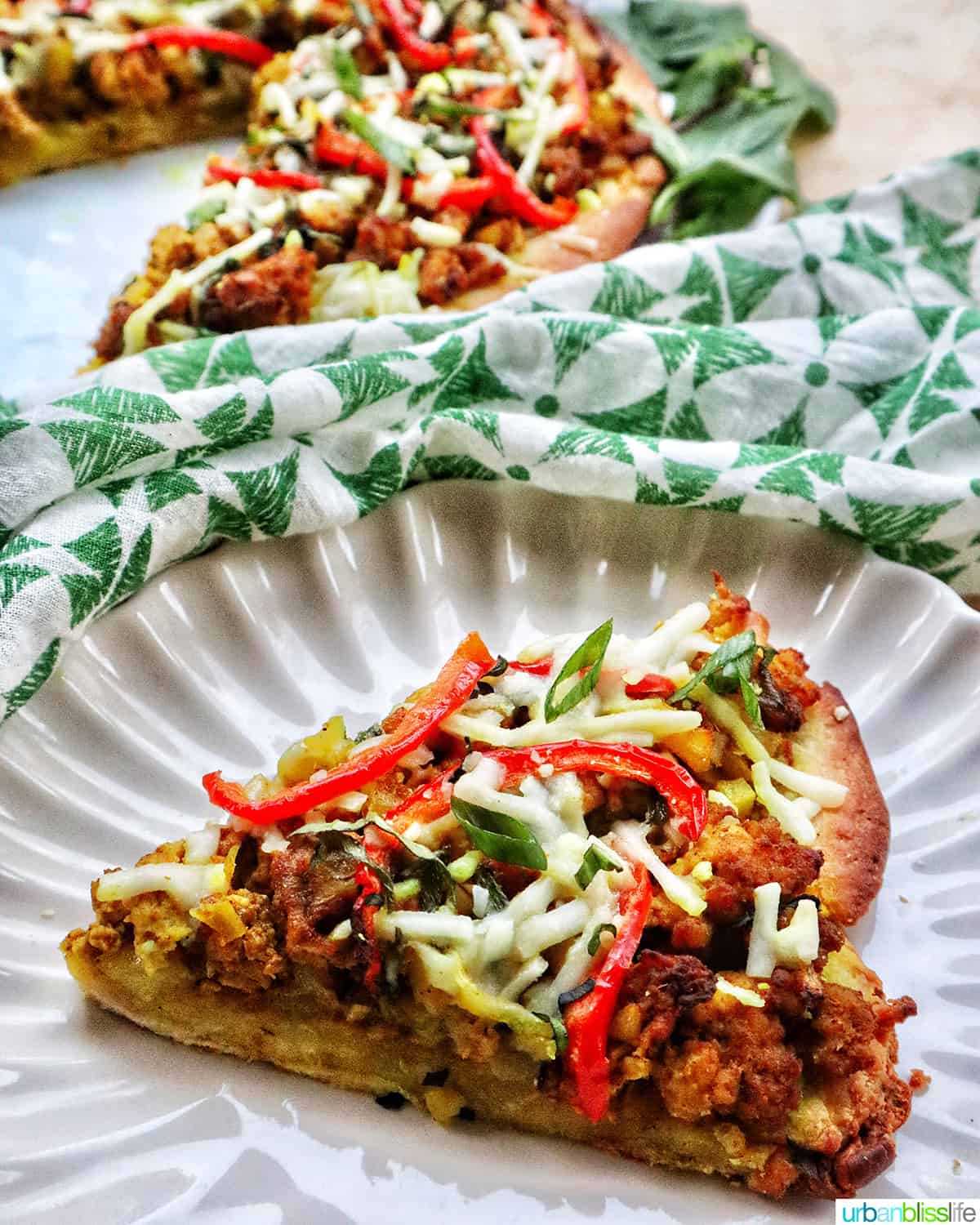 slice of Thai curry pizza on a plate next to an almost full pizza.