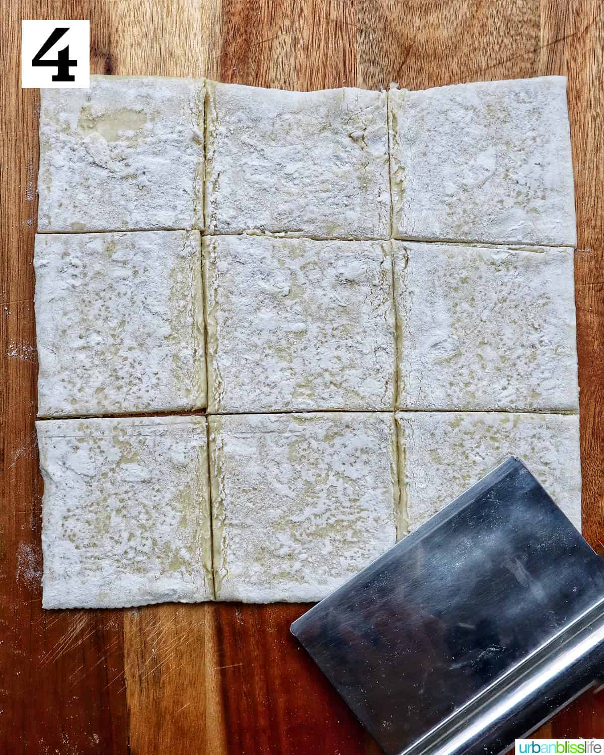 puff pastry cut into 9 squares on a cutting board with pastry bench.