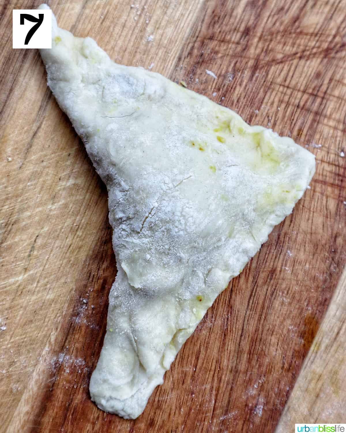 folded puff pastry to make triangle Thai curry puffs on a cutting board.