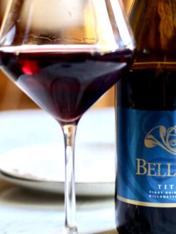 glass of red wine next to a bottle of Bells Up Winery pinot noir.