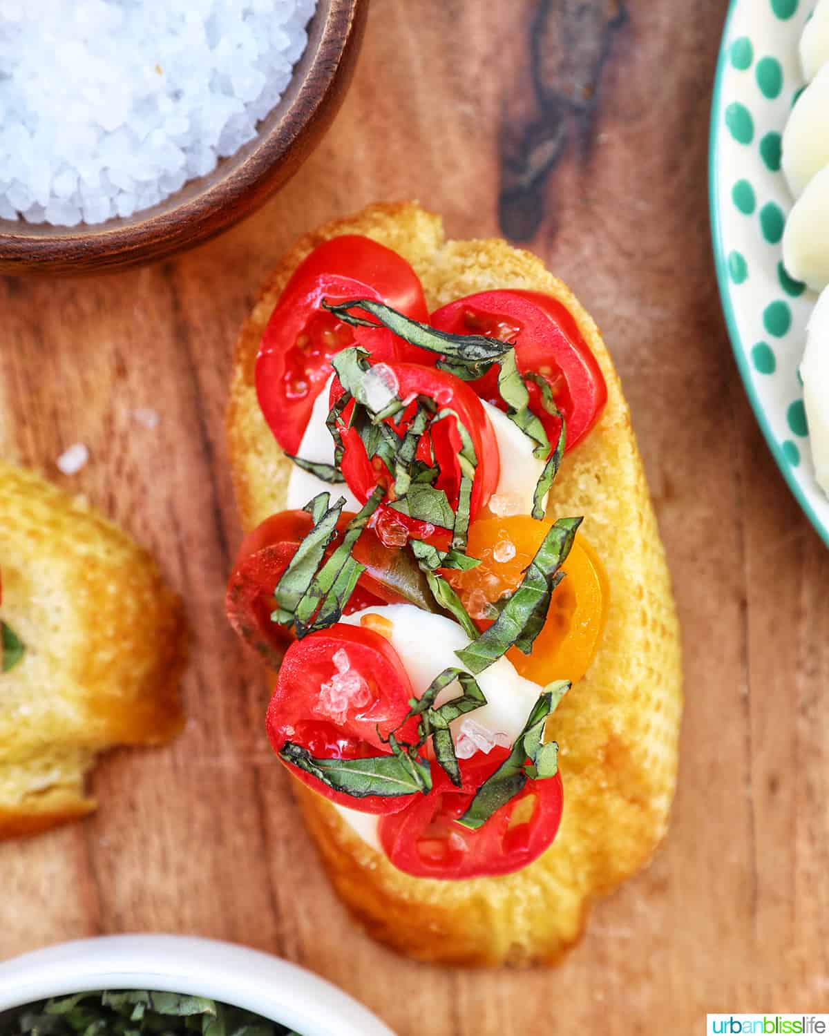crostini with tomatoes, mozzarella, and basil on a wooden board.