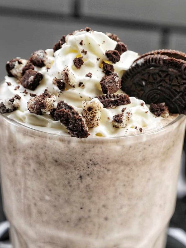 Cookies & Cream Milkshake in a tall glass with whipped cream topping and crushed Oreo cookies on top.