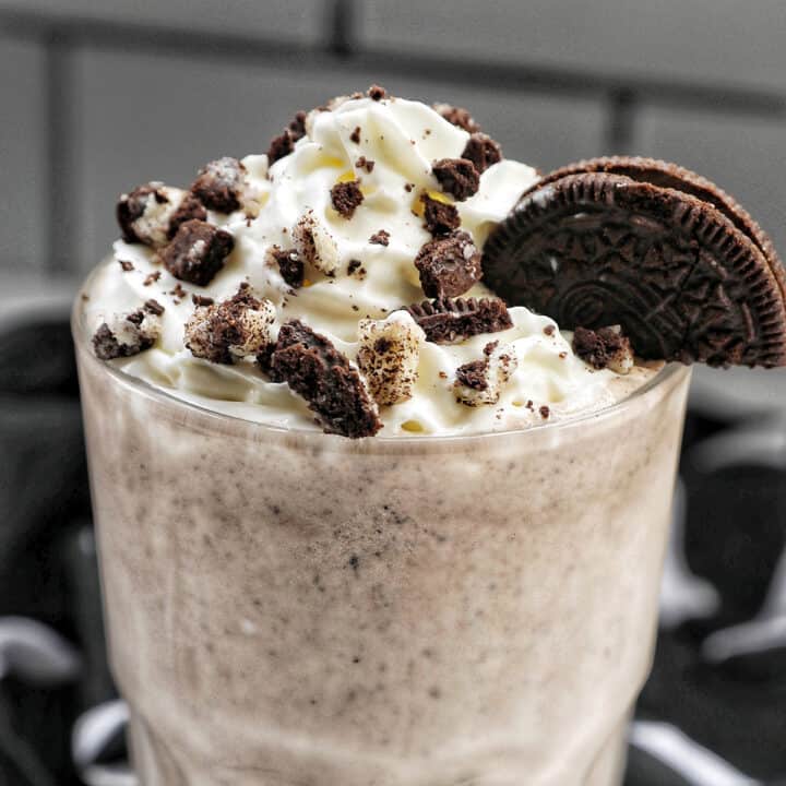 Cookies & Cream Milkshake in a tall glass with whipped cream topping and crushed Oreo cookies on top.