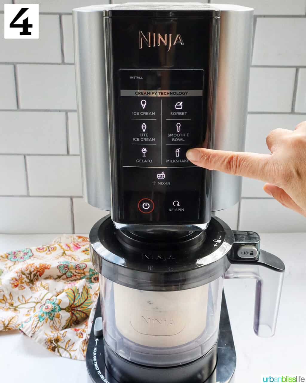 finger pressing the Milkshake setting on the Ninja Creami machine.