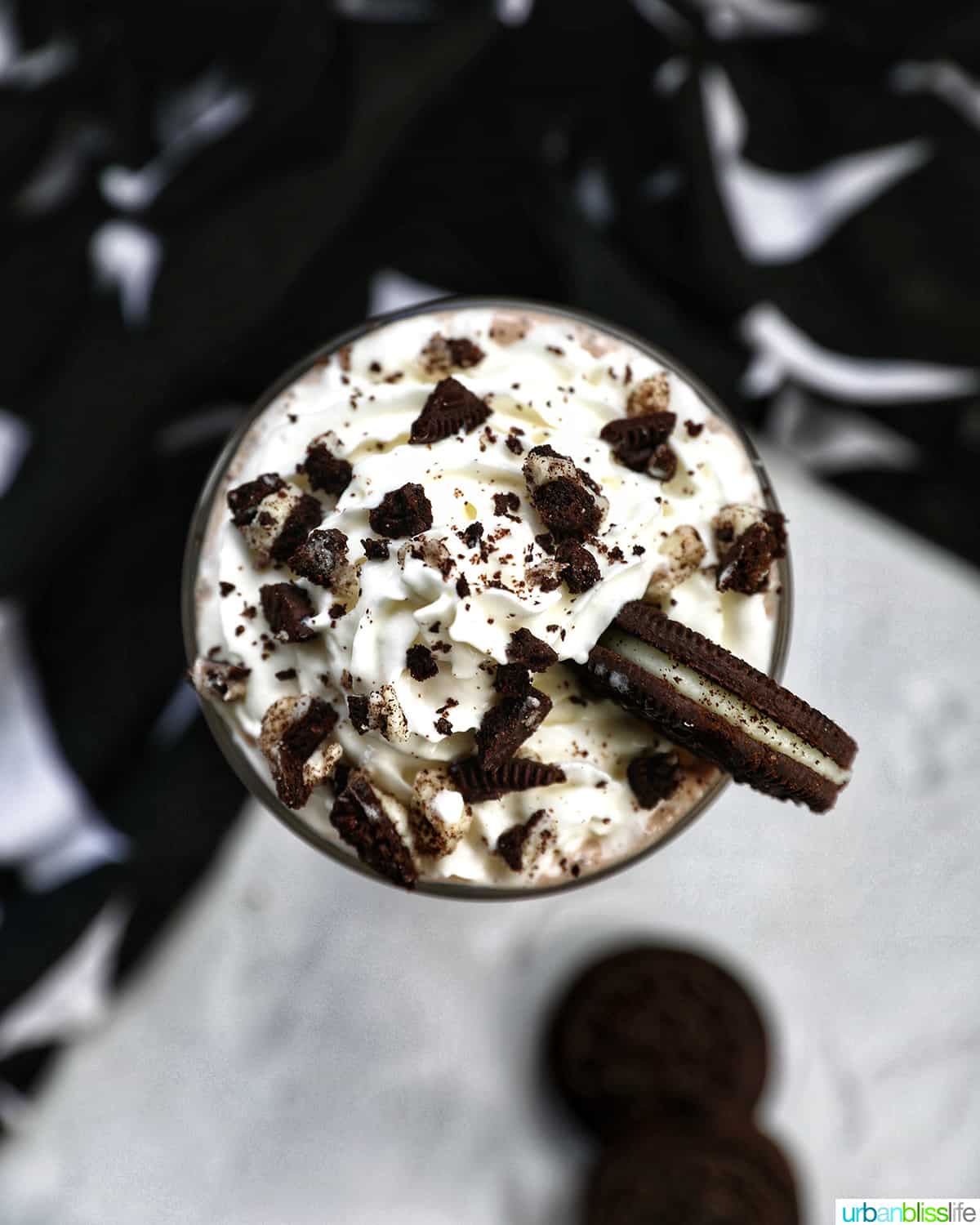 overhead photo of Cookies & Cream Milkshake in a tall glass with whipped cream topping and crushed Oreo cookies on top.