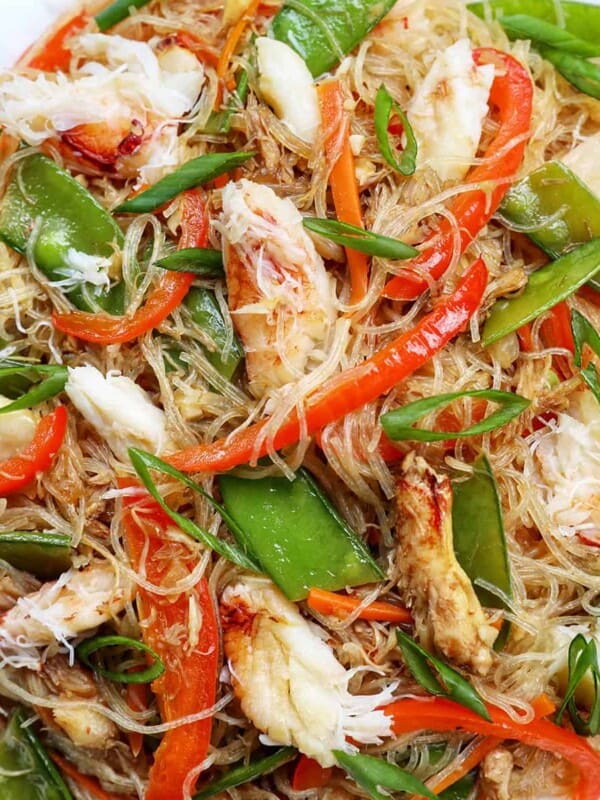 crab pancit filipino noodles in a large bowl, with slices veggies and chunks of crab meat.