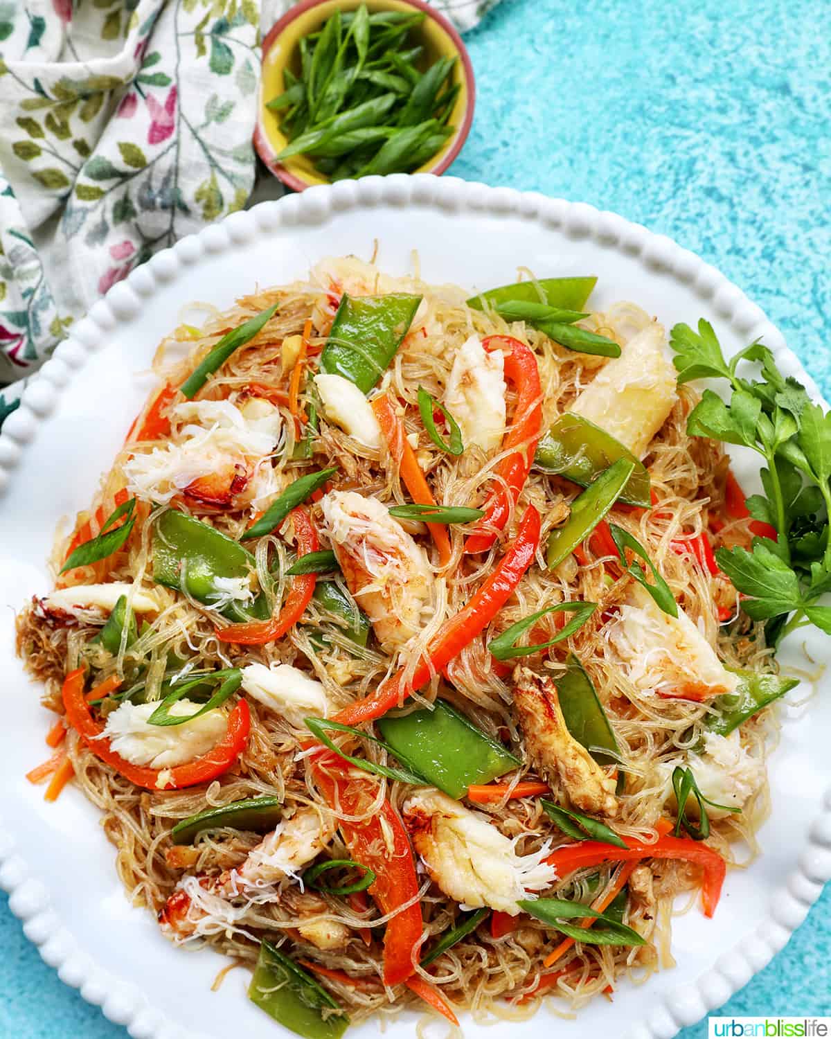 crab pancit filipino noodles in a large bowl, with slices veggies and chunks of crab meat.