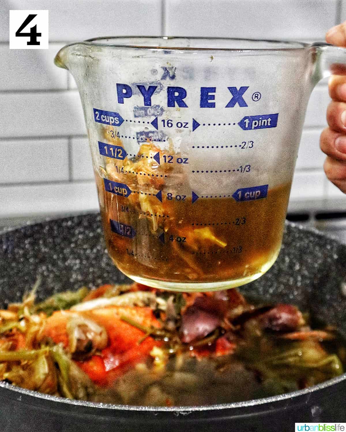 crab stock in a glass Pyrex measuring cup over a large pot of crab stock.