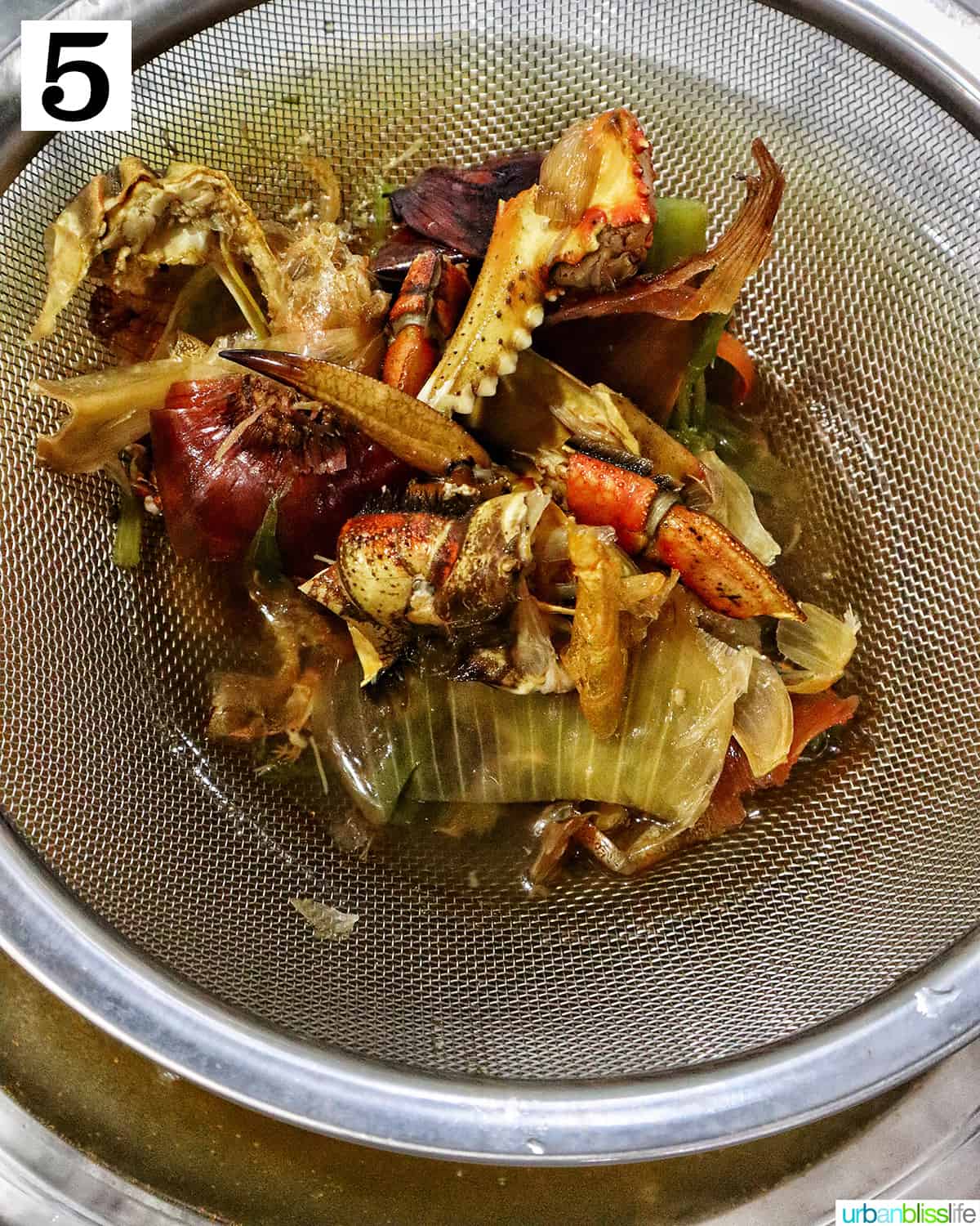 straining out the liquid and capturing the seafood and vegetable scraps in a sieve.