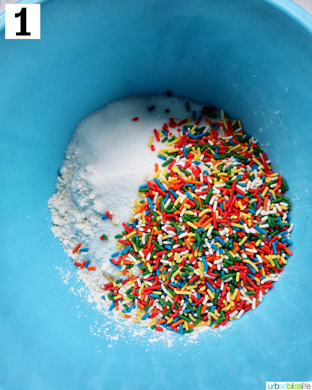 large blue bowl with colorful sprinkles and dry ingredients to make funfetti baked goods.