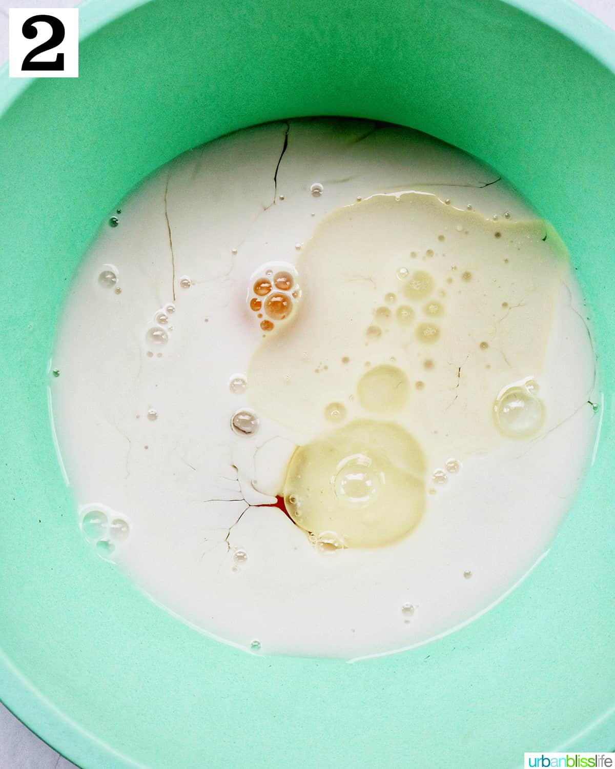 large green mixing bowl with wet ingredients for recipe.