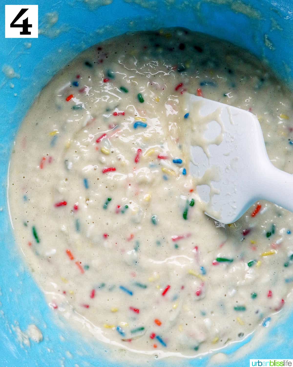 large bluw mixing bowl with ingredients to make funfetti pancakes with a spatula.