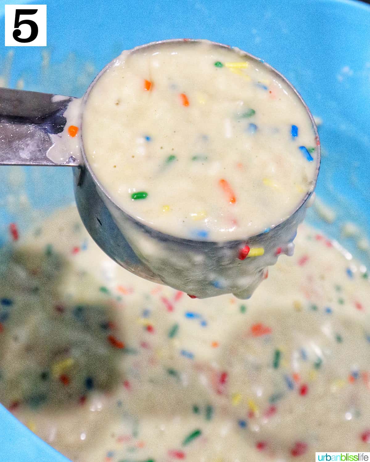 metal measuring cup with batter for funfetti pancakes.