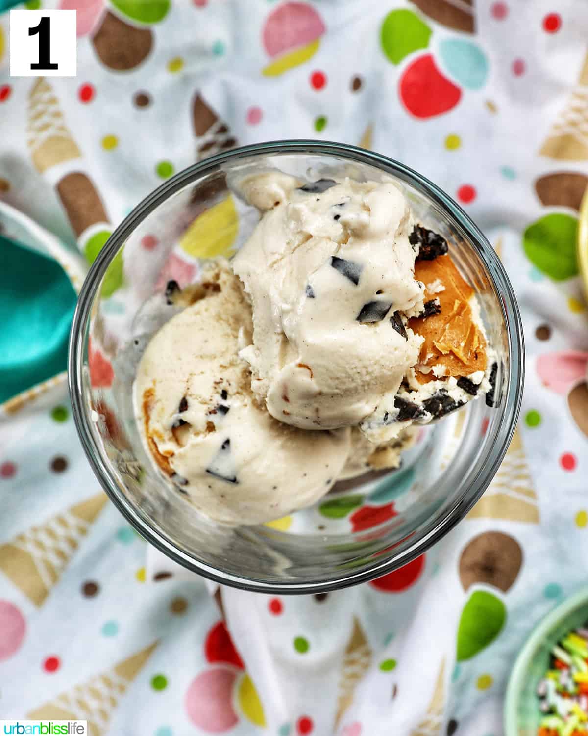 scoops of ice cream in a parfait glass on colorful fun kitchen towel.