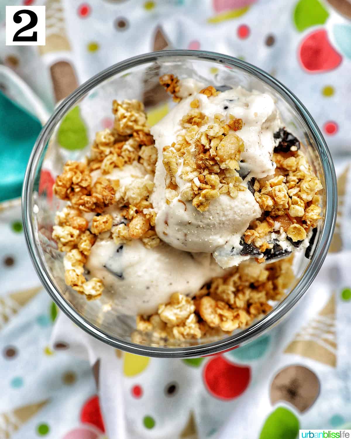 ice cream parfait topped with granola, on a colorful kitchen towel.