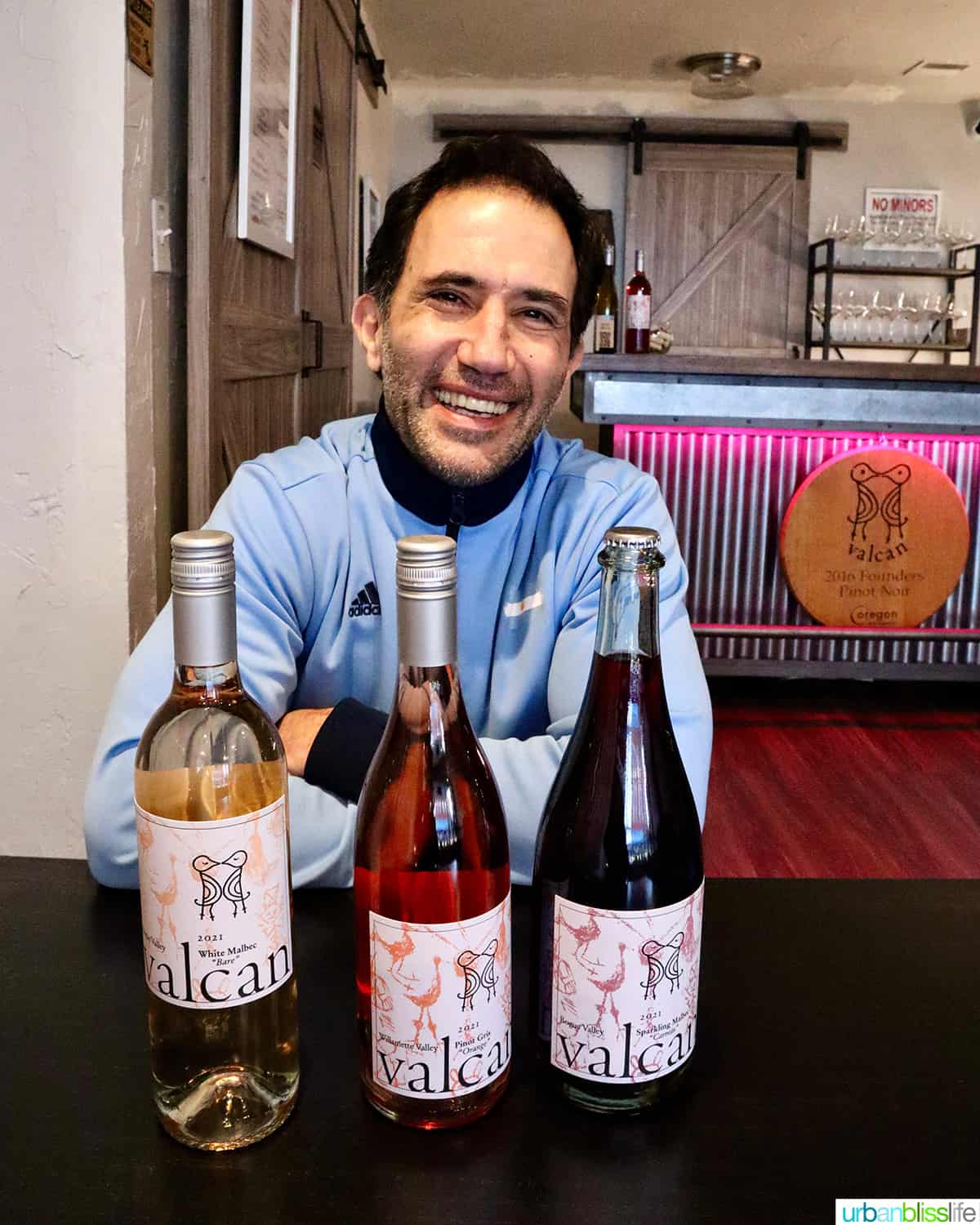 JP Valot, owner and winemaker of Valcan Cellars, with three bottles of wine in the tasting room.