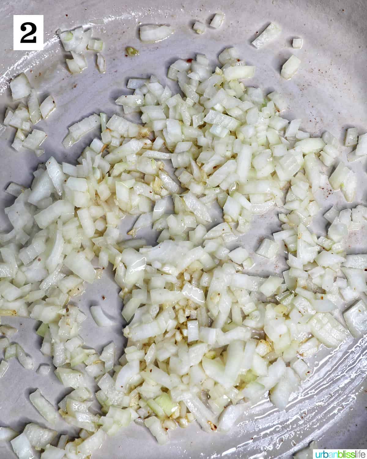 diced onions and minced garlic sauteing in a saucepan.