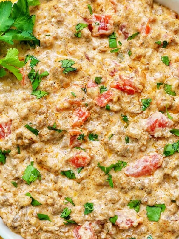 taco dip with ground beef, tomatoes, and cilantro in a large white bowl.
