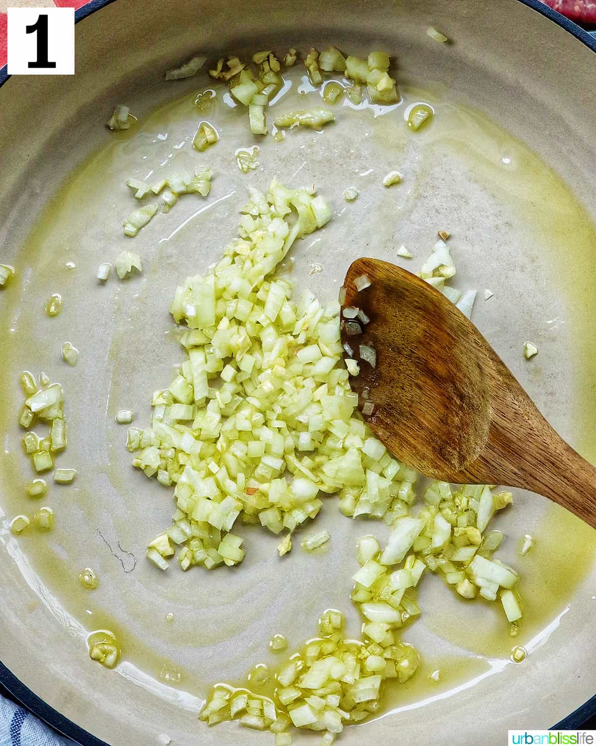 wooden spoon sautéing garlic and onions in a saucepan.