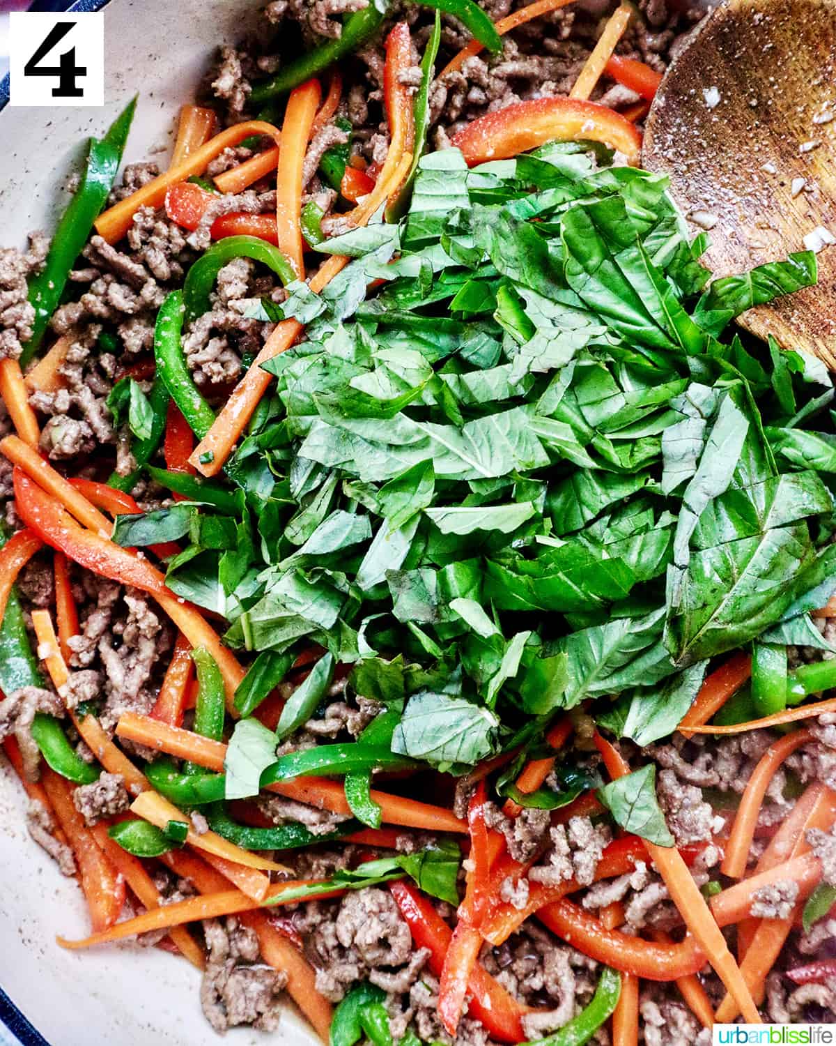 fresh basil leaves over ground beef with vegetables.