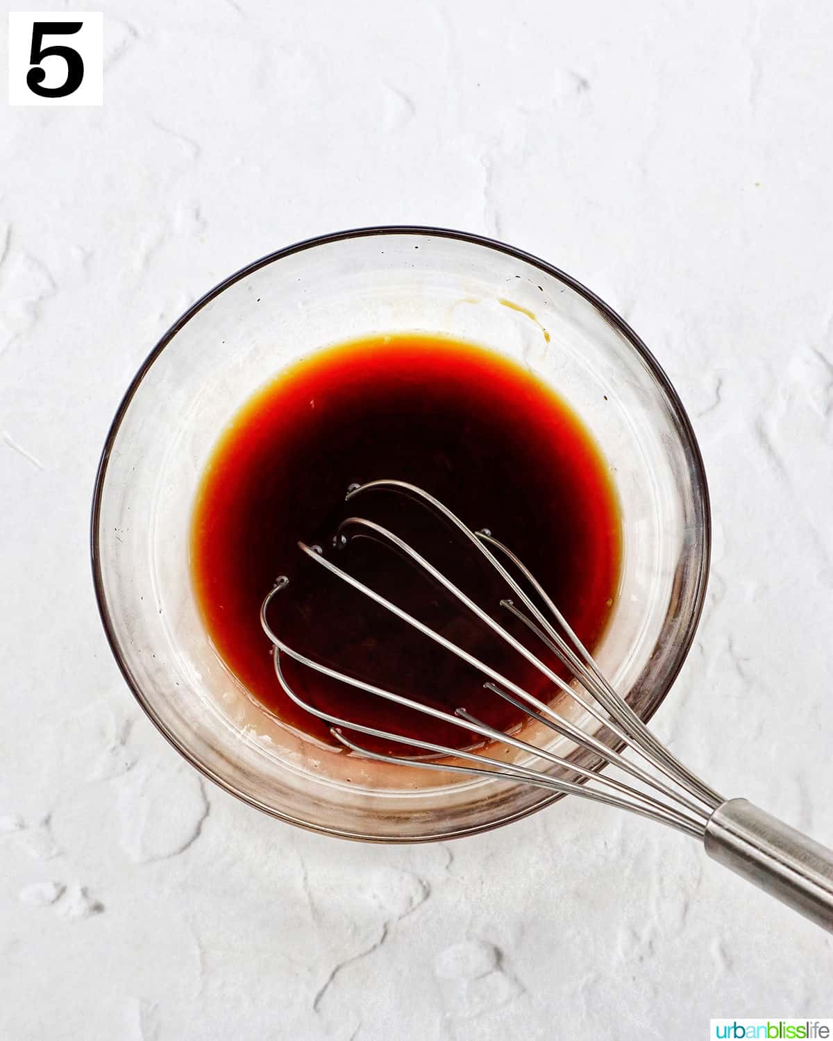 clear glass bowl with asian marinade sauce and a whisk.