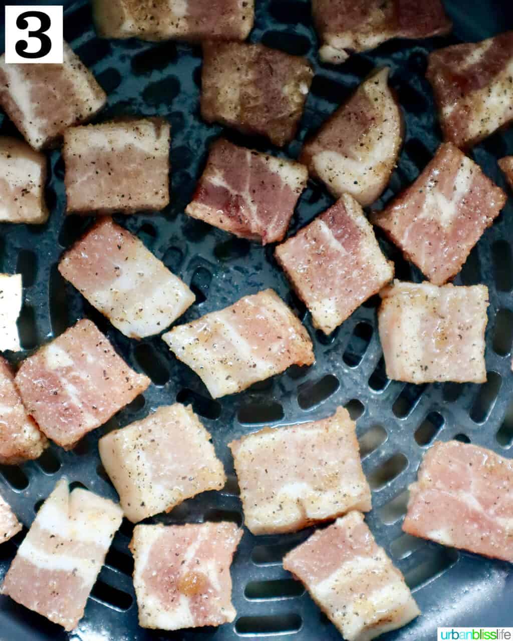 pork belly bites in an air fryer basket, uncooked.