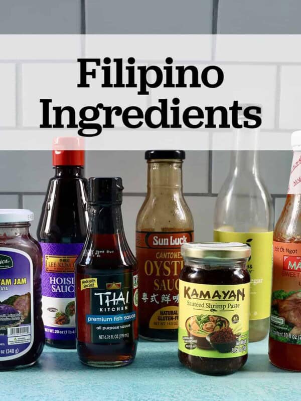 several jars and bottles of Filipino ingredients used in Filipino cuisine on a blue table with text that reads Filipino Ingredients.